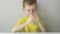 A little boy in a yellow T-shirt drinks water from a glass.