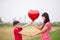 Little boys giving balloon heart to his mother with love