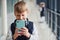 Little boywith phone and headphones standing if front of school kids in uniform that together in corridor. Conception of education