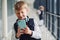 Little boywith phone and headphones standing if front of school kids in uniform that together in corridor. Conception of education