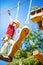 Little brave caucasian girl at outdoor treetop climbing adventure park