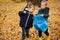 Little brother and sister collect trash using litter picker in forest at autumn