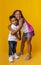 Little brother and sister hugging and smiling on yellow background