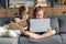 little brother and sister using laptop and reading book while relaxing