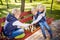 Little brothers playing chess with sister on bench in park. Children intelligence development. Family leisure time. Kids playing