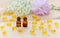 Little brown bottles with neroli and rose essential oils, gold capsules of natural cosmetic, flowers blossom on the