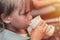 little candid kid boy five years old eats food and drinking from a paper cup sitting in