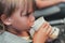 Little candid kid boy five years old eats food and drinking from a paper cup sitting in airplane seat on flight traveling. childre