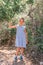 Little candid tired kid girl traveler and hiker of eight years old in a blue striped dress travels and hiking a mountain path amon