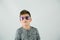 Little caucasian boy standing in a studio setting on a white backdrop with rock star purple sunglasses and attitude.