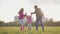 Little caucasian child holding hands of her father and elder sister and jumping up. Positive family in casual clothes