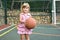 Little caucasian girl with ball on outdoor playground. children`s sports for health.