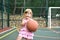 Little caucasian girl with ball on outdoor playground. children`s sports for health.