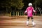 A little caucasian girl beginner roller in the autumn park in the rainy day.