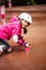 A little caucasian girl beginner roller falling on the ground in the autumn park in the rainy day.