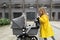 Little caucasian girl with blonde hair walking with newborn baby sibling outdoor. Colors of the year 202: ultimate gray
