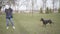 Little Caucasian girl kicking away barking dog in park. Wide shot of frightened kid and angry domestic animal outdoors