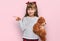 Little caucasian girl kid hugging teddy bear stuffed animal smiling happy pointing with hand and finger to the side