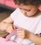 A little caucasian girl peels off a pink felt sticker with her fingers while sitting at a children's table