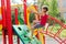 Little caucasian girl playing on playground, climbing the wall on a rope