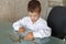 Little caucasian manager boy counting coins on desk