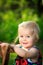 Little caucasian toddler stands using chair for support outside