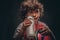 Little champion boy in sportswear holds a ball and drinking water from a bottle. on a dark textured background.