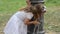 Little charming baby girl in a dress drinking water from a Roman fountain on a hot summer day