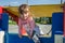 Little charming baby girl playing on a playground, riding on a swing on a bright sunny day