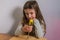 Little charming girl child twists a screwdriver screw into a wooden board