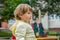 Little charming girl in the yellow jacket baby playing in the park outdoor rides, riding on the teeter