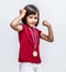 Little cheeky girl with medals smiling, showing young female power