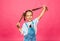 Little cheerful girl in denim overalls pulls her hair in different directions. children