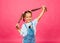 Little cheerful girl in denim overalls pulls her hair in different directions. children