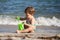 Little cheerful happy kid playing with a bucket and scoop sitting on the seashore