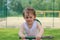 Little cheerful preschooler girl rides on a swing on the playground on the background of a football field