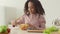 Little chef. African american girl preparing lunch herself, cutting vegetables and mixing salad at kitchen