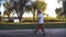 Little child with blonde hair walking on the trail in park at summer. Kid going on green grass at summer. Happy boy