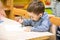 Little child boy drawing with colorful pencils in preschool at table in kindergarten