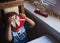 Little child boy hiding behind red heart shaped gift box with bow near window in daylight