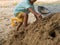 Little child boy playing and climbing sand pile outdoor with dirty foot, hand.