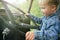 Little child boy playing inside old vintage truck car, holding big wheel. Slow life in countryside. Happy childhood concept.Focus