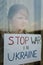 Little child calls No War, raises banner with inscription Stop war in Ukraine. Kid at the window. Stop russian aggression.