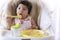 Little child celebrating her first birthday with cake at home. Baby adorable girl with apron holding spoon in her hand while