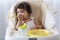 Little child celebrating her first birthday with cake at home. Baby adorable girl with apron holding spoon in her hand while