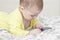 Little child with a cell phone. Baby 7 months interested in the smartphone, lies on the bed and pokes a finger at the screen of