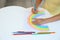 Little child drawing rainbow at white table, closeup. Stay at home concept