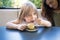 Little child eating sugar with spoon from coffee cup