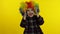 Little child girl clown in rainbow wig making silly faces. Having fun, smiling, dancing. Halloween