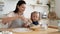 Little child girl in flour watching young mommy stirring eggs.